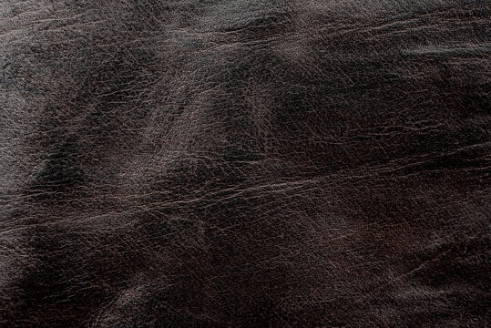 Brown leather texture. Worn piece of leather closeup