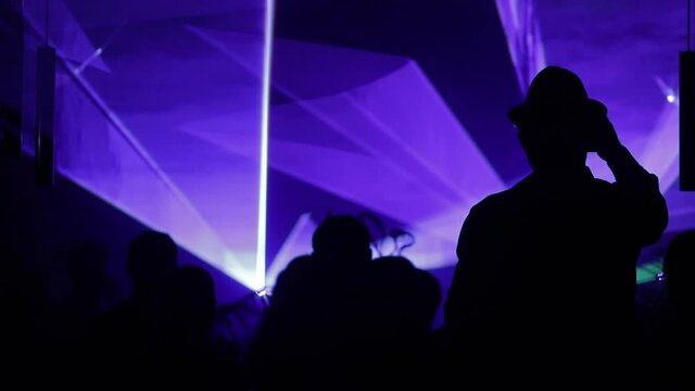 Silhouette of a crowd of people on the background of the stage with laser light