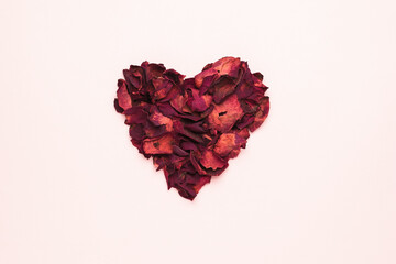 A beautiful heart made of dried rose petals on a pastel background. The concept of a romantic relationship.