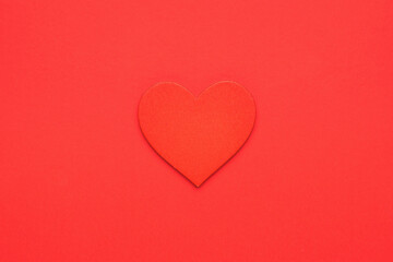 Red wooden heart on a bright red background. The concept of falling in love and Valentine's day. Minimalism.