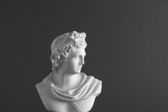 Plaster classical statue on a dark gray background.
