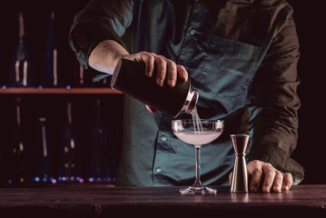 Bartender's hands serving cocktails on bar counter in a restaurant, pub. Mixed drinks. Alcoholic cooler beverage at nightclub on dark background