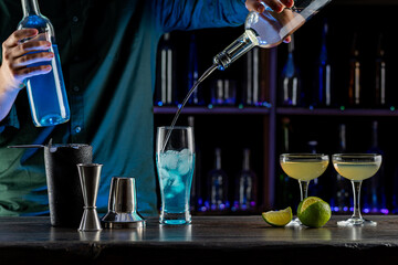 Bartender's hands serving cocktails on bar counter in a restaurant, pub. Mixed drinks. Alcoholic cooler beverage at nightclub on dark background