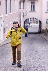Fototapeta na wymiar A middle-aged business man in a yellow jacket walks down the street and talks on the phone