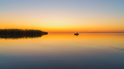 Obraz premium Orange sunset on a quiet lake, sunset reflected in calm water