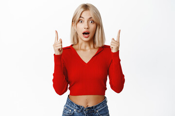 Image of enthusiastic blond woman pointing fingers up, demonstrating advertisement, showing promo...