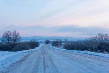 Obraz na płótnie Canvas Snowy road outside the city at dawn.