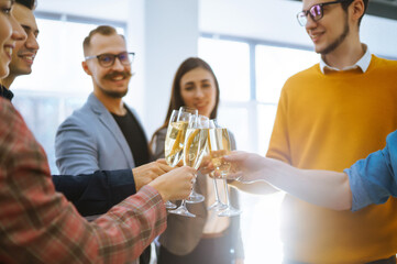 Fototapeta na wymiar Clinking glasses with champagne. Happy coworkers celebrating their business achievement on a party in the office. Partners celebrating their victory. 