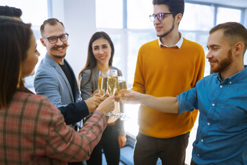 Clinking glasses with champagne. Happy coworkers celebrating their business achievement on a party in the office. Partners celebrating their victory. 