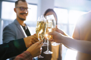 Clinking glasses with champagne. Happy coworkers celebrating their business achievement on a party in the office. Partners celebrating their victory. 