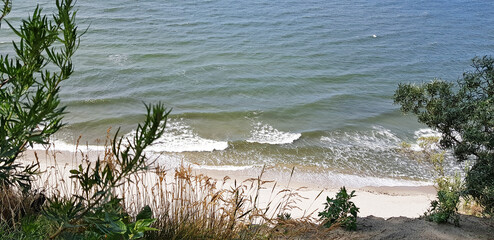 view of the sea sandy shore and the blue-green sea with waves from the cliff