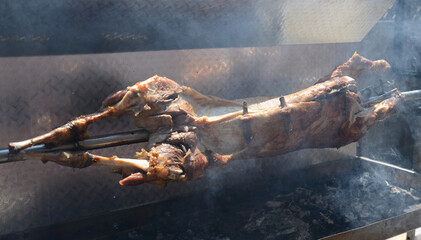Traditional dairy lamb cooked on a charcoal grill. Roast a small lamb whole over an open fire. Organic lamb on a spit.
