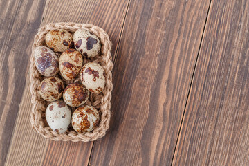 Group of quail eggs are put on clear tray on wooden table.