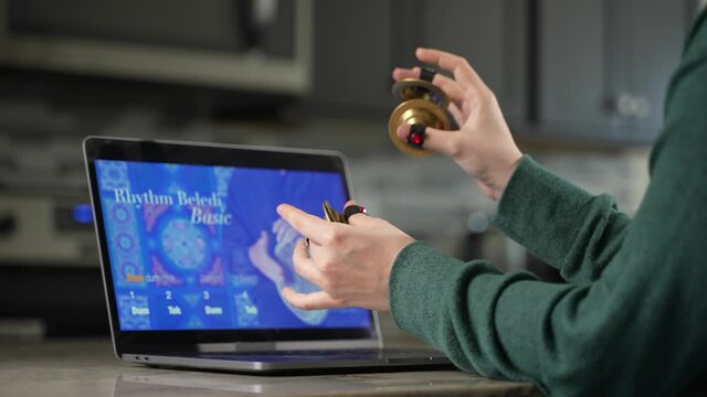 Woman takes remote lesson to learn finger cymbals online on a laptop. Remote learning concept.