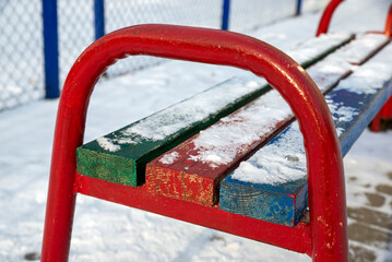 benches on the playground are covered with snow