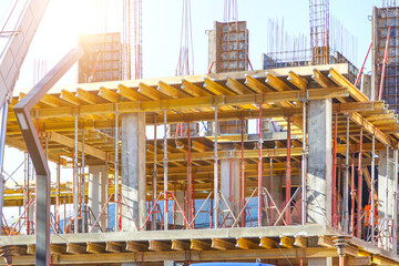 Building construction site work against blue sky.Hydraulic luffing jib tower cranes and workers...