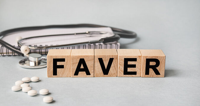 FAVER inscription on wooden cubes isolated on white background, medicine concept. Nearby on the table are a stethoscope and pills.