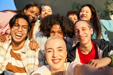 Happy centennial taking smiling selfie. Group of multiethnic students together at campus...