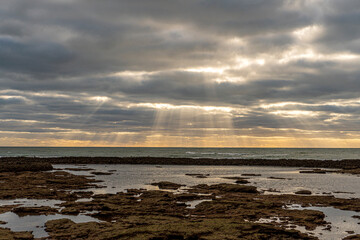 Obraz premium Hermosa panorámica del atardecer con los reflejos del sol atravesando las nubes y cayendo sobre el mar en la playa de Chipiona (Cádiz)