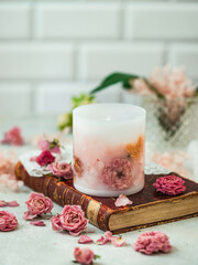 Handmade candles of a unique design, with different flowers, dry leaves on a light background. Candles made from organic wax, paraffin wax. Relaxation atmosphere. Luxurious lifestyle.