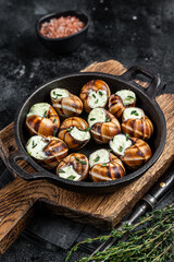 Delicatessen food - Bourgogne Escargot Snails with garlic butter in a pan. Black background. Top view