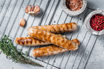 Fototapeta Grilled Bratwurst pork meat sausages on a grill. Gray background. Top view obraz