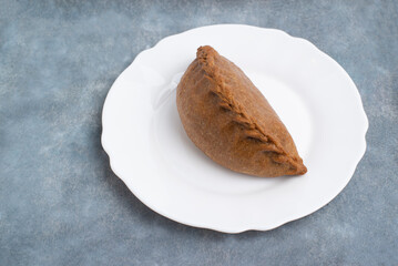 a pie made of rye bread on a white plate on a gray background