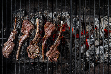 Grilled lamb mutton chop steaks on barbecue, outdoor BBQ grill with fire. Top view