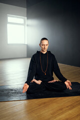 The yogi man do pranayama in the lotus position with gyan mudra. Yoga practice in the studio.