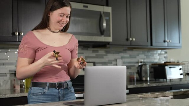 Smiling woman takes remote lesson to learn finger cymbals online on a laptop. Remote learning concept.