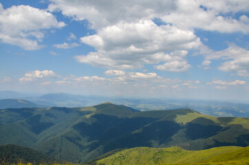 Panorama of mountains covered with dense forests in the rays of sunlight on a summer day. Carpathians, Ukraine