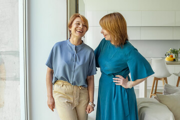 Two smiling positive mature women laughing and chatting