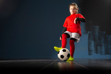 The girl football player is having fun with the ball indoors