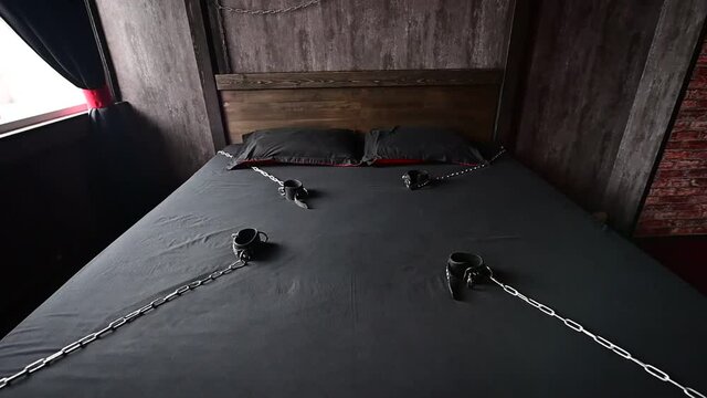 BDSM Leather handcuffs for role-playing games on a gray sheet. Bondage for carnal pleasures. Domination and submission. Departing camera. No people