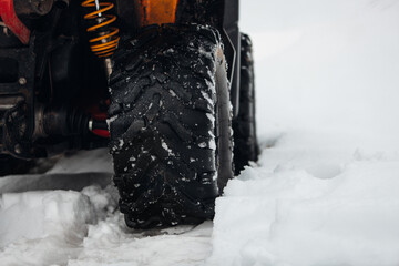 The rear tire of the quadbike in winter forest 