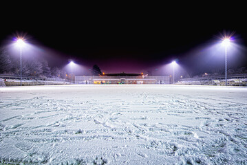 snowy soccer stadium, football stadium covered with snow sport field in the dark - obrazy, fototapety, plakaty