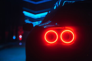 Supercar led taillight at the night city street, rear view