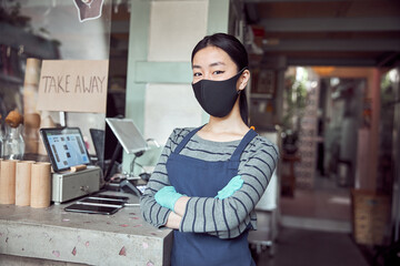 Fototapeta premium Portrait of young woman in face mask working in cafe