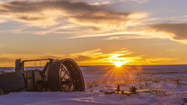 time lapse view of sunset over wyoming pasture with broken down vehicle and cows in winter