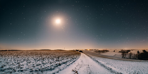 Panorama of freshly fallen snow on a field and a starry sky with a full moon
