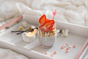 Chia pudding with muesli and strawberries. candy in the shape of a heart, breakfast in bed on a tray