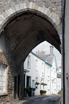 street of old picturesque houses through the arch of the medieval gatehouse in the village of cartmel in cumbria