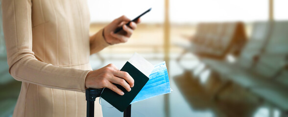 Passenger holds passport with luggage in hand and mobile phone. Immunite passport or certificate...