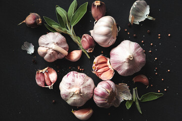 Garlic bulbs, spices, herbs and garlic cloves on a black background.