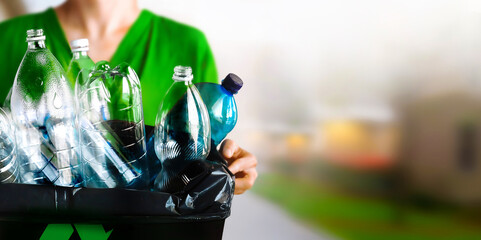 A woman holding a recycle bin with plastic bottles in the outdoors © Katarina