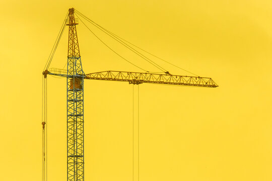 Construction Industrial Crane Against The Backdrop Of A Yellow Sunny Sky And Sunset