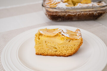 Slice of apple cake with biscuit base close up on a white plate. Fresh baked delicious homemade apple cake, breakfast, dessert