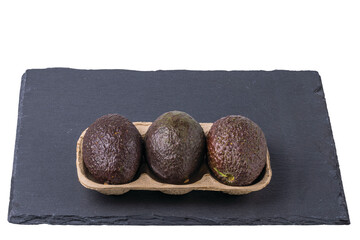 Close up view of avocado package isolated on a black rock cutting board.