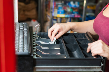 hand of an enterprising latina woman in her business opening the cash register. girl in front of cash register taking out money after making a sale. concept of economy