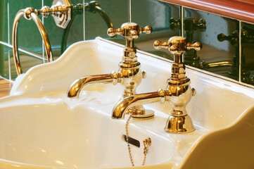 New luxury hotel vintage brass gold plated pillar taps in ensuite bathroom at wash basin - obrazy, fototapety, plakaty